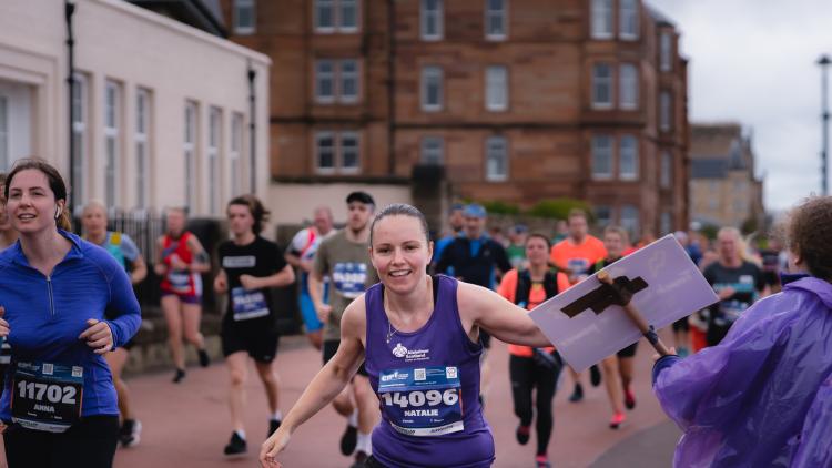 A runner touches a support sign from Alzheimer Scotland