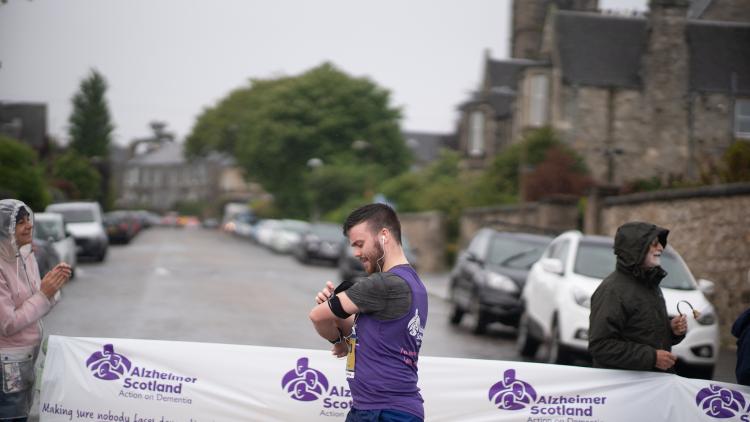 A man walks past an Alzheimer Scotland banner