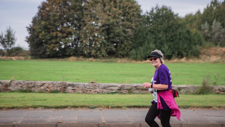 A women in a purple top runs along a street
