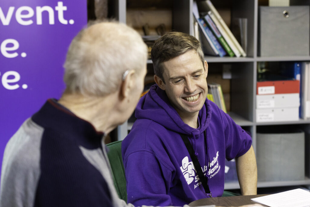 Alzheimer Scotland member of staff listening to man at support group