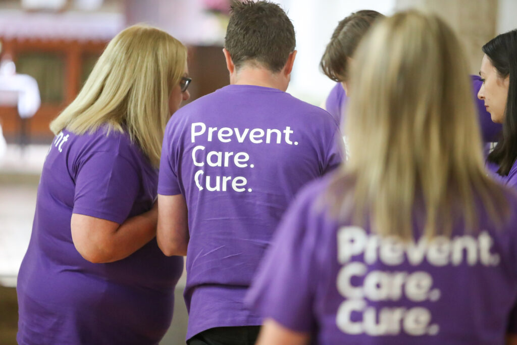 A group of people in purple Alzheimer Scotland t-shirts with Prevent. Care. Cure. printed on them