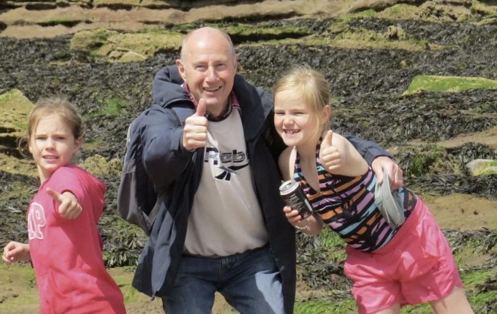 Grandfather at beach with granddaughters