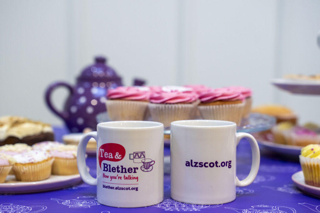 Tea and Belther branded mugs on a table with cakes