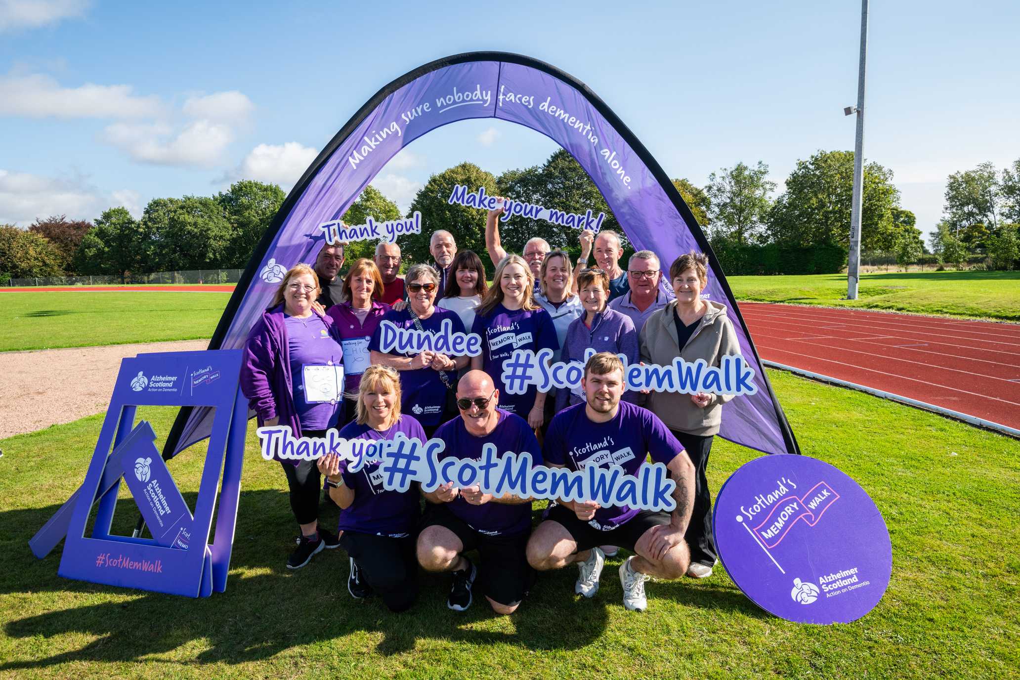 Group of supporters in purple under an arch for the Alzheimer Scotland Dundee Memory Walk
